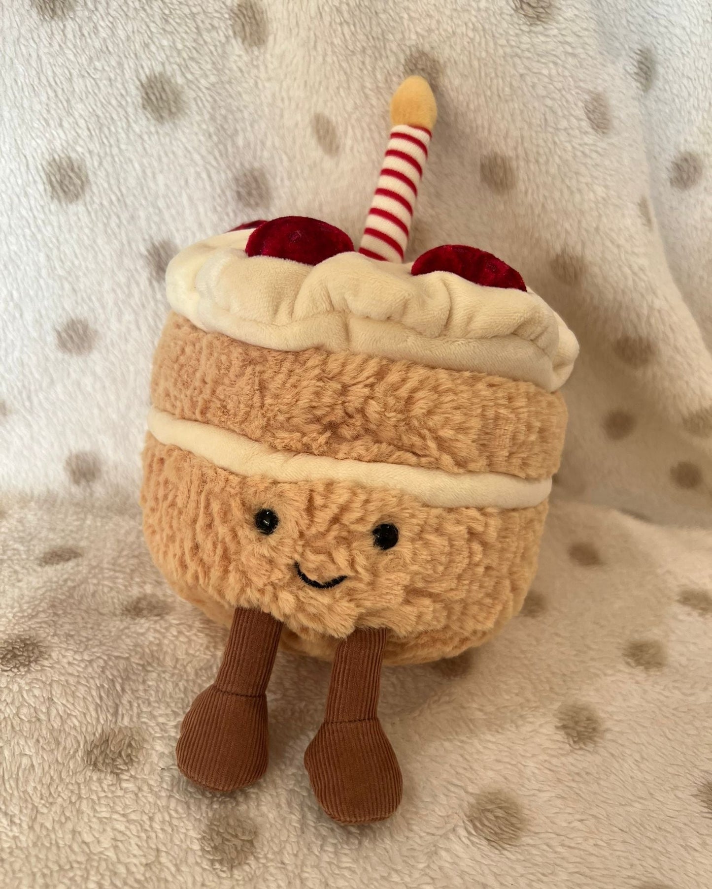 Plush toy resembling a ice cream sundae with a smiling face on a polka dot background