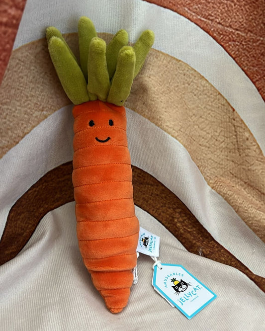 Carrot-shaped plush toy with a tag on a striped fabric background