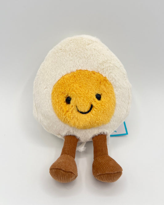 Plush toy resembling a fried egg with a smiley face on a light gray background
