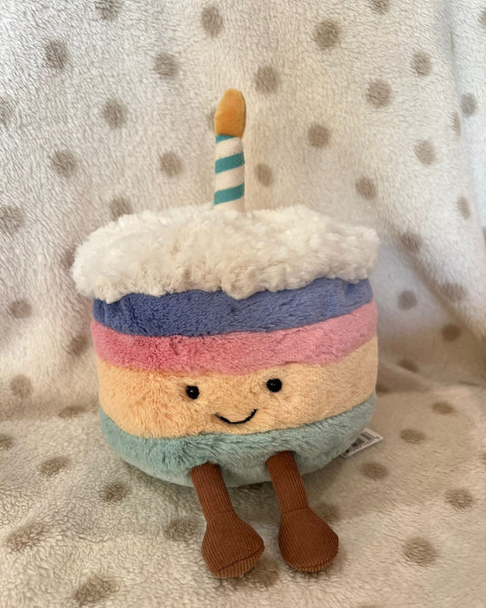 Plush toy resembling a birthday cake with a candle on a polka dot background