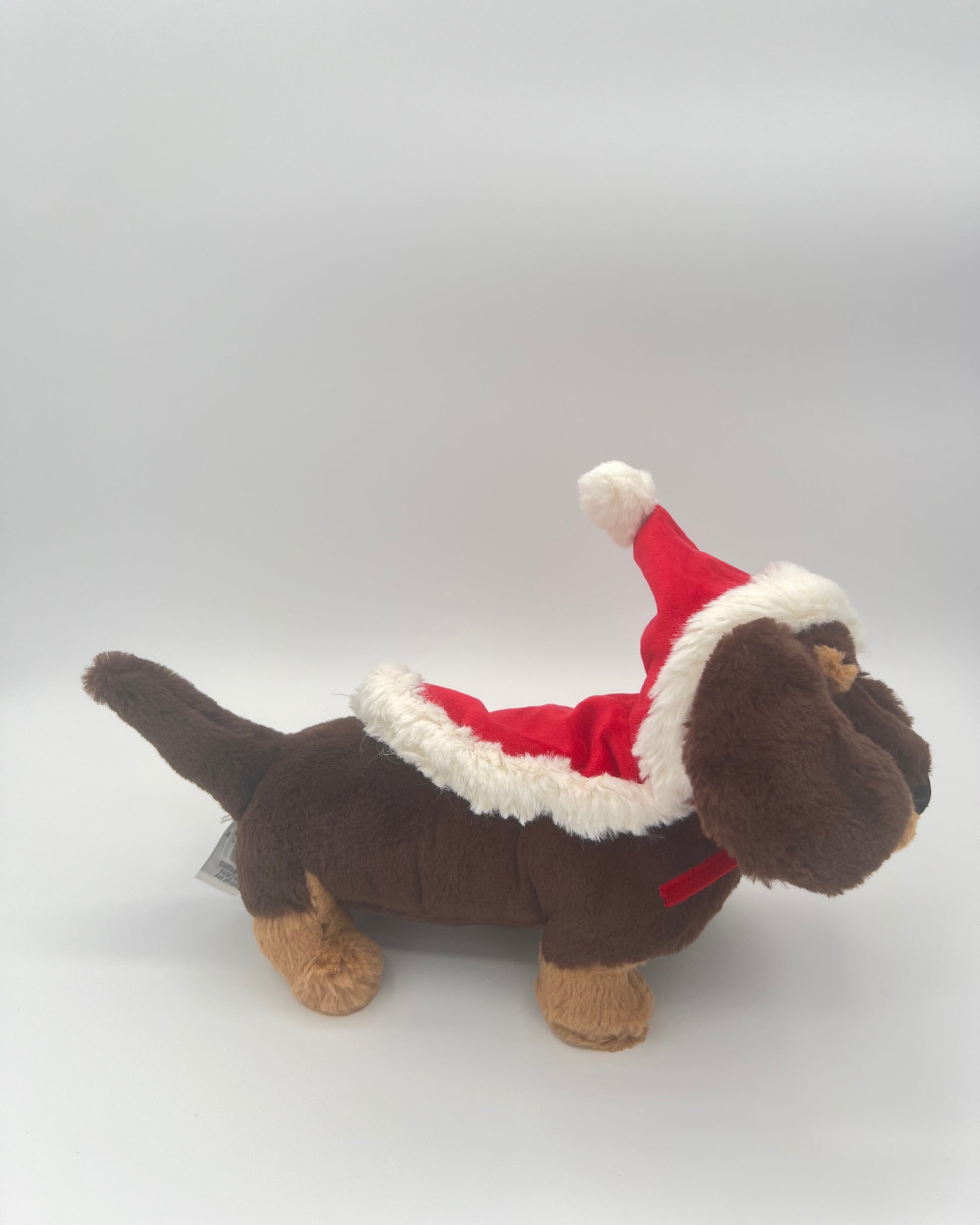 Plush toy dog in a Santa outfit on a white background