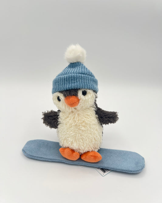 Plush penguin toy with a blue knitted hat on a light gray background