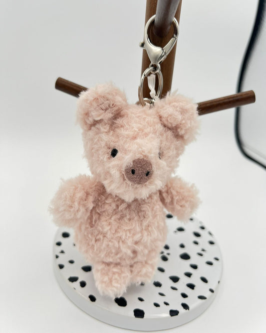 Plush Piggy keychain on a stand with a white background